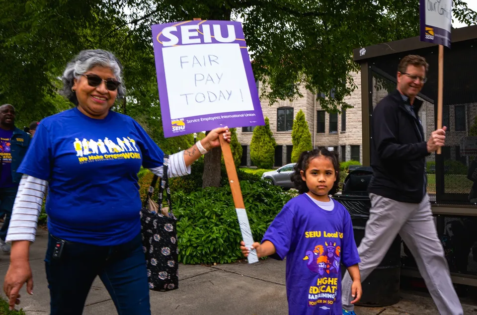 A Local 083 member and child carry an SEIU Fair Pay Today sign during the June 30 rally