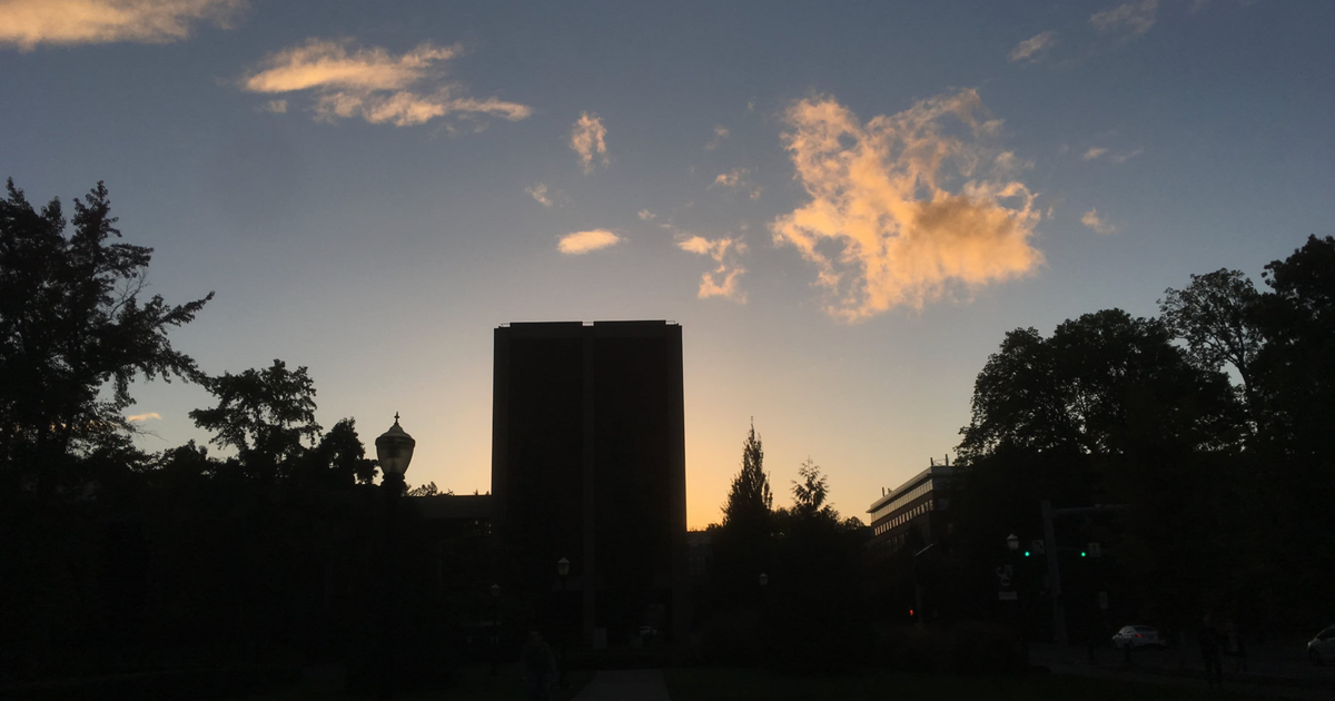 Kerr Administration Building at Oregon State University silhouetted against an orange sunset and dark blue sky.