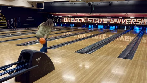 A Local 083 member rolls an orange bowling ball at the OSU bowling alley